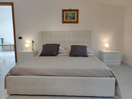a white bedroom with a large bed with two night stands at B&B Privileged in Pollena Trocchia