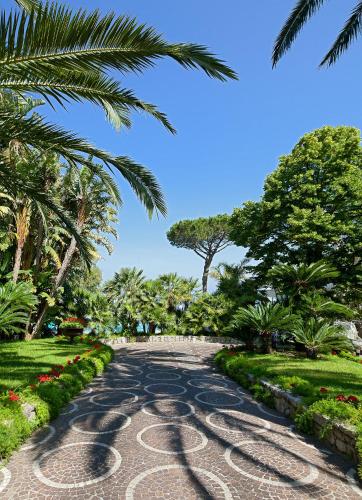 a cobblestone road in a park with palm trees at Grand Hotel Riviera in Sorrento