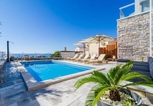 a swimming pool with chaise lounge chairs and a house at Apartments Villa Capitano in Mlini