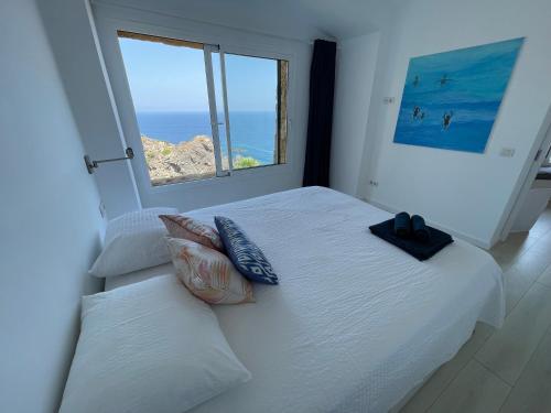 a bedroom with a white bed with a large window at Cap Sa Sal - Sa Roca 3 in Begur