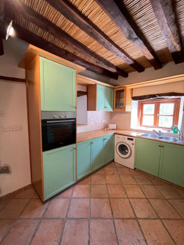 a kitchen with green cabinets and a washing machine at Stone built country house in Louvaras Village in Louvaras