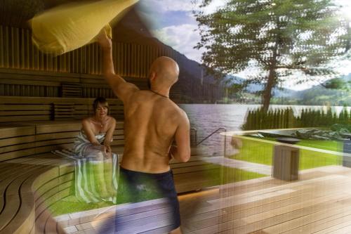a man and a woman sitting in a sauna at Familien- Sportresort BRENNSEEHOF in Feld am See