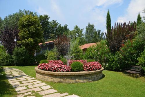 a garden with a fountain and flowers in the grass at Park Residence Il Gabbiano in Moniga