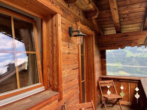 eine Holzhütte mit einem Fenster und einem Stuhl in der Unterkunft Kama Alm in Aschau