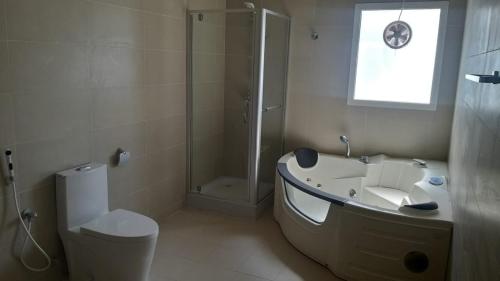 a bathroom with a tub and a shower and a toilet at Luxury Garden Villas Complex in Salalah
