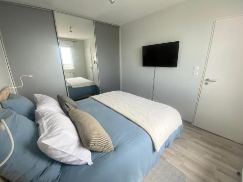 a bedroom with a bed with pillows and a television at Appartement de standing VUE MER in Berck-sur-Mer