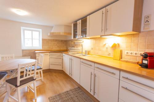 a kitchen with white cabinets and a table at FULL HOUSE Premium Apartments Halle City KU15 in Halle an der Saale