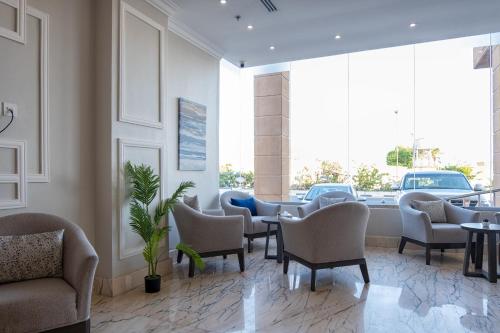 a waiting room with chairs and tables and windows at فندق كارم in Raḩīmah