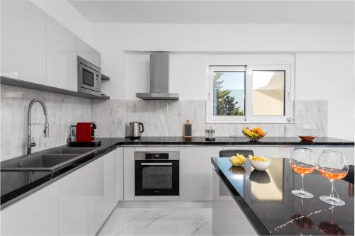 a white kitchen with two wine glasses on a counter at Viviane Paulos Villa in Gennadi