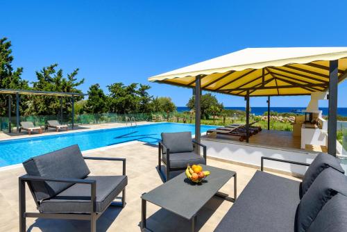 a patio with chairs and a pool with a umbrella at Viviane Paulos Villa in Gennadi