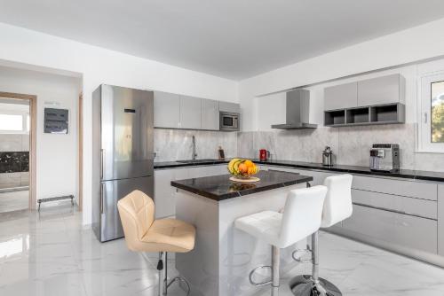 a kitchen with a island with white counter chairs at Viviane Paulos Villa in Gennadi