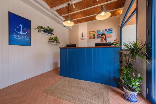 a woman standing behind a blue counter in a room at Áncora Salou La Siesta Apartments in Salou