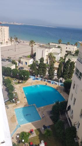 einen Luftblick auf einen Pool neben dem Strand in der Unterkunft Appartement 2 chbres Piscine Renove Veranda Gde Terasse Vue panoramique Au bord de mer Sur corniche de Tanger A proximité de la plage in Tangier