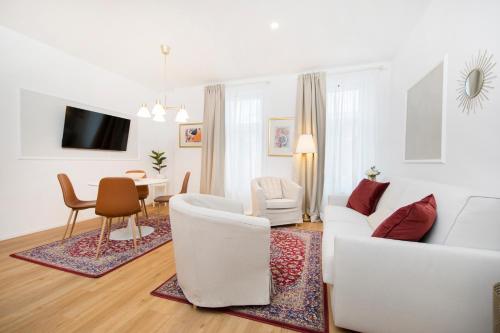 a living room with white furniture and a dining room at Cozy apartments in Ljubljana