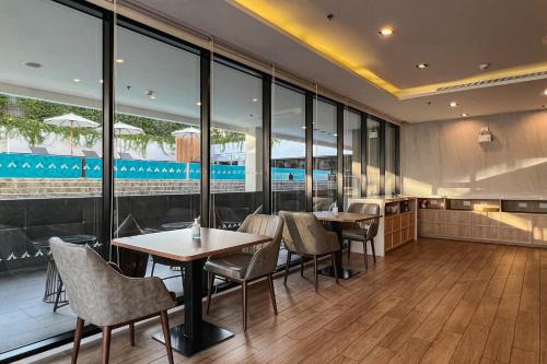 a restaurant with tables and chairs and large windows at Amanta Hotel & Residence Sathorn in Bangkok