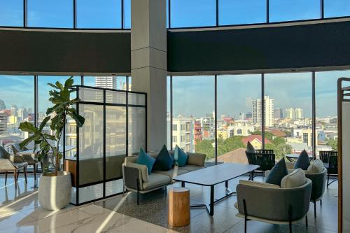 a lobby with a table and chairs and windows at Amanta Hotel & Residence Sathorn in Bangkok