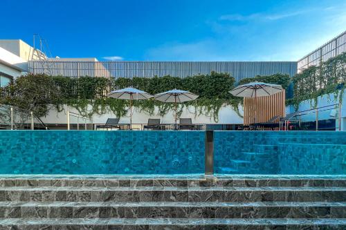 a swimming pool with chairs and umbrellas in front of a building at Amanta Hotel & Residence Sathorn in Bangkok