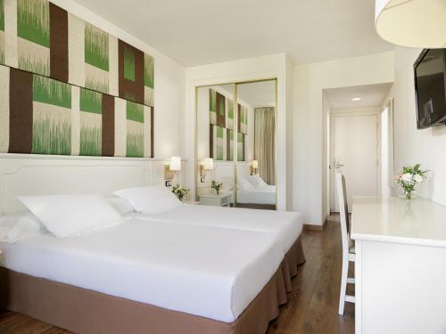 a white bedroom with a bed and a bathroom at H10 Salou Princess in Salou