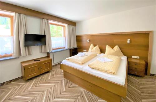 a bedroom with a bed and a flat screen tv at Pension Appartements Gabriele in Bad Gastein