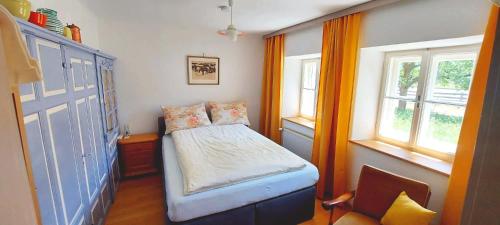 a small bedroom with a bed and two windows at Fallerhaus in Gmünd in Kärnten