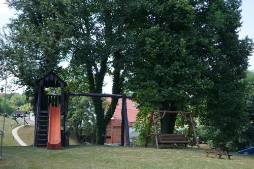 a park with a playground with a tree and a swing at Deluxe Apartments Franjkovic in Seliste Dreznicko