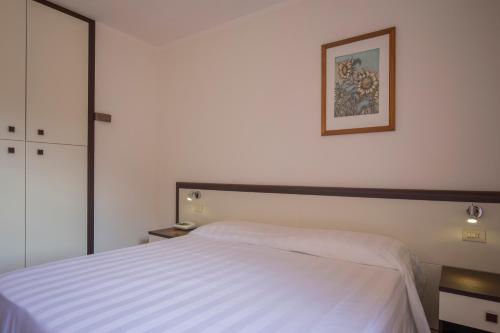 a bedroom with a white bed and a picture on the wall at Hotel Fabricia in Portoferraio