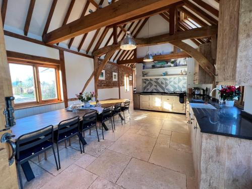 eine große Küche mit einem langen Tisch und Stühlen in der Unterkunft Beautiful country barn with hot tub and amazing views in Princes Risborough