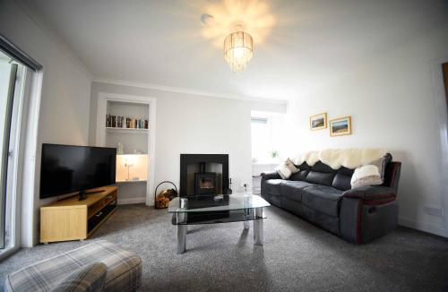 a living room with a couch and a tv at Tigh Beag Na Mara in Roag