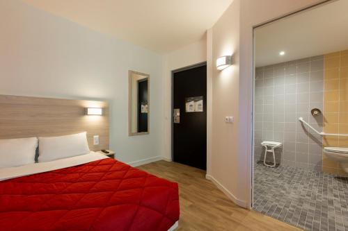 Habitación de hotel con cama roja y baño. en Premiere Classe Nantes Ouest - St Herblain en Saint-Herblain