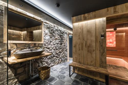 a bathroom with a sink and a stone wall at Le Moulin Noir à 400m du circuit in Francorchamps