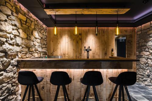 a bar with black stools in front of a stone wall at Le Moulin Noir à 400m du circuit in Francorchamps