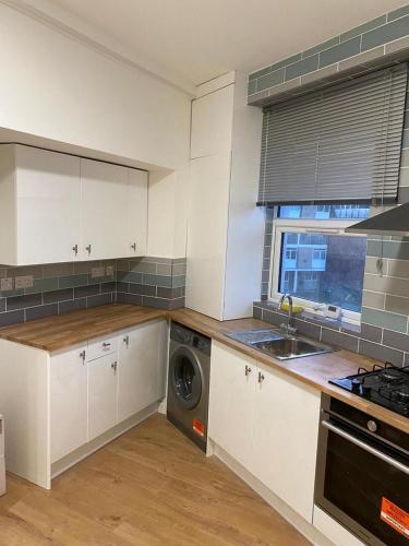 a kitchen with white cabinets and a washing machine at Newly refurbished flat in camberwell, london in London