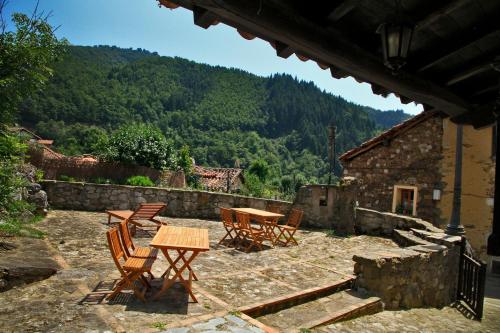 a patio with a table and chairs and a mountain at La Posada de la Xana in Llanuces