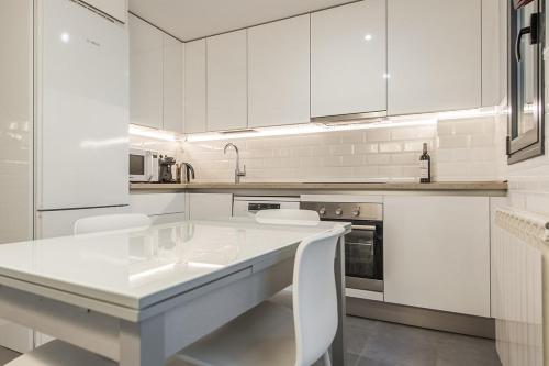 a kitchen with white cabinets and a white table and chairs at EXCLUSIVE BUILDING SWIMMING POOL - MADRID RIO CITY CENTER in Madrid