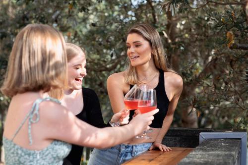 two women are laughing while holding wine glasses at Large Family Sized Unit with Watersports, Maroochy River, Lagoon, and Beach Access in Twin Waters