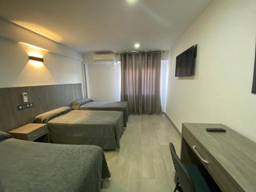 a hotel room with two beds and a television at Hostal Goyma III in San Fernando de Henares