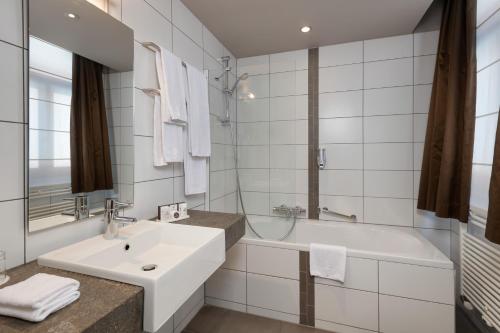 a white bathroom with a sink and a tub at Martin's Patershof in Mechelen