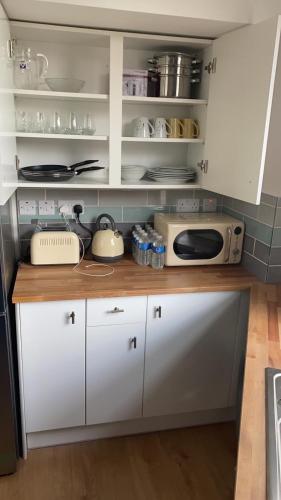 una cucina con armadietti bianchi e forno a microonde di Newly refurbished flat in camberwell, london a Londra