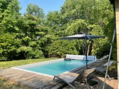 basen z parasolem, krzesłem, stołem i parasolem w obiekcie Belle Villa basque avec piscine et jardin de 3000m2 w mieście Saint-Jean-de-Luz