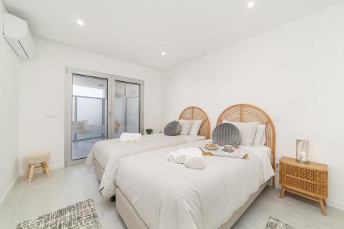 two beds in a white room with a window at Nazaré Views X - By SCH in Nazaré