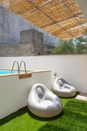 two white beanbags sitting on the grass next to a pool at Villa Franitu - Corsano in Corsano