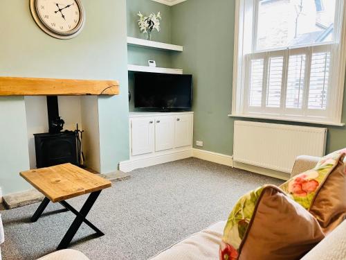 a living room with a clock on the wall and a tv at Ilkley Cottage in Ilkley