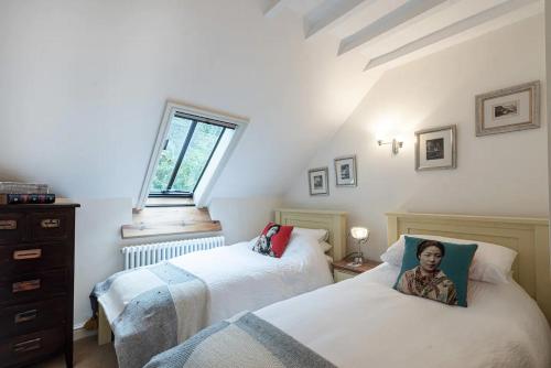 a attic bedroom with two beds and a window at Converted Chapel, Stunning Sea & Mountain Views! in Penmaen-mawr
