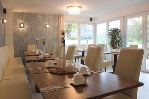 a dining room with tables and chairs and windows at Pension Amo Marem in Dierhagen