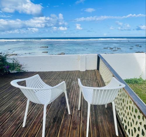 two white chairs sitting on top of a boardwalk near the beach at Villa Maimouna les pieds dans l'eau in Saint-Pierre
