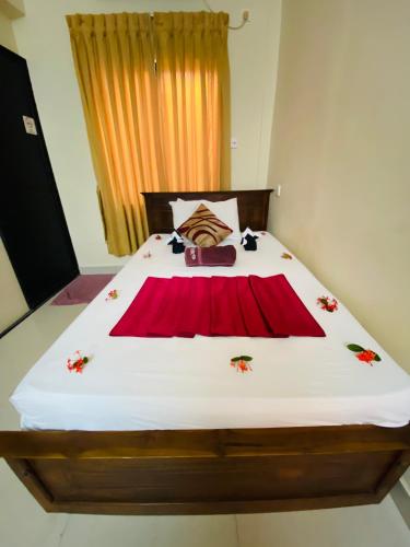 a bedroom with a bed with a red blanket on it at Yal's Town Inn in Jaffna