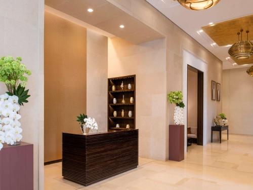 a lobby of a hotel with vases of flowers at Alwadi Hotel Doha - MGallery in Doha