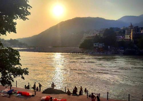 a group of people standing on the shore of a river at Vedic Dham Ganga in Rishīkesh