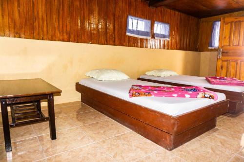 a bedroom with two beds and a desk and a table at Reggae Guest House in Tuk Tuk