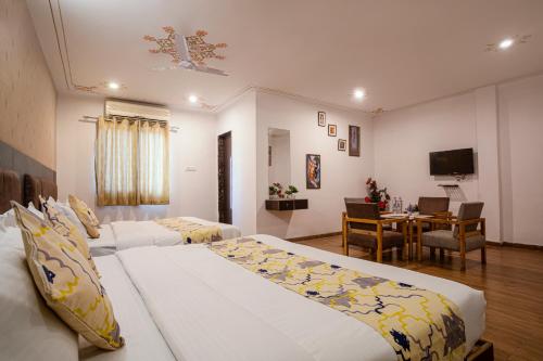 una camera d'albergo con due letti e una sala da pranzo di Tripli Hotels Arunoday Palace a Udaipur